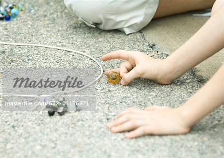 Children playing marbles on asphalt