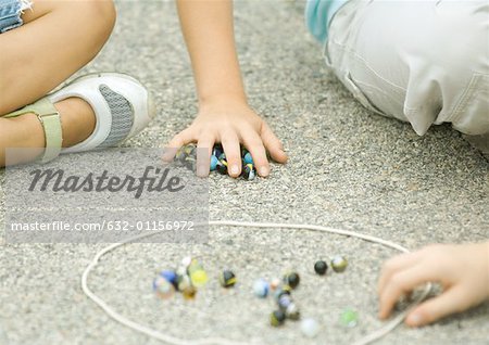 Children playing marbles on asphalt