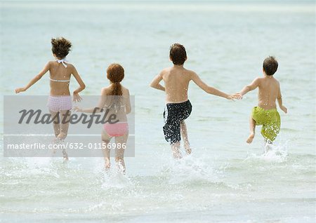 Children running in surf at beach