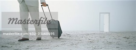 Businessman with suitcase on beach, doorway in background