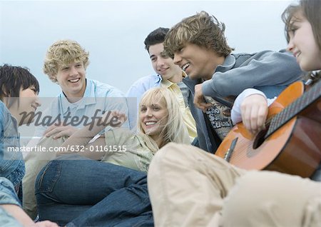 Friends hanging out together, one playing guitar