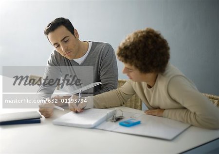 Father helping teenage son with homework