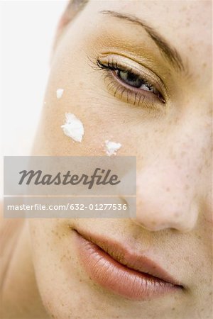 Woman's face with dots of moisturizer under eye, cropped view