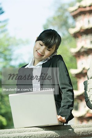 Young woman using laptop and cell phone
