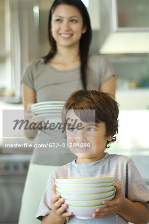 Mother and son carrying stacks of dishes