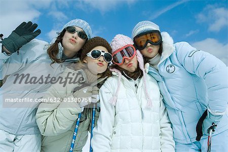 Four female friends dressed in ski clothing, puckering at camera, portrait