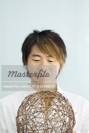 Man holding wicker sphere, smiling, head and shoulders