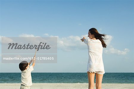 Woman and boy catching clouds, ocean horizon in distance