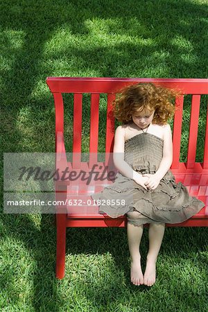 Girl sitting on red bench, high angle view