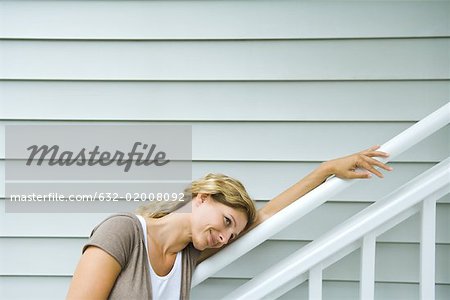 Woman leaning head against railing, smiling, looking away