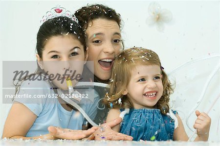 Woman celebrating with daughters on her lap, confetti everywhere