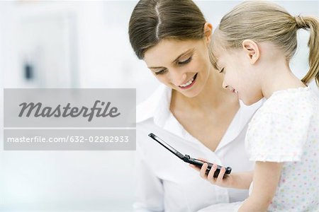 Mother and young daughter looking at cell phone together