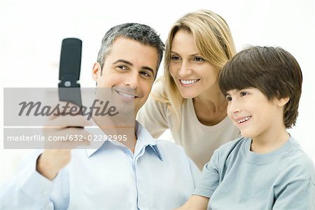 Family looking at cell phone together, smiling