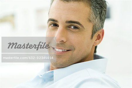 Man smiling at camera, looking over shoulder, portrait