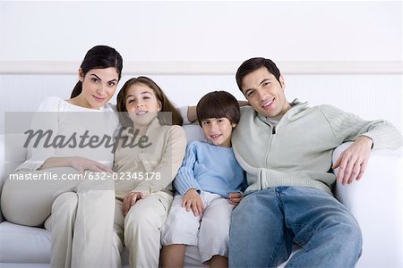 Family with two children sitting together on sofa, portrait