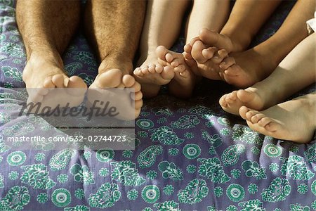 Group of bare feet on bed, close-up