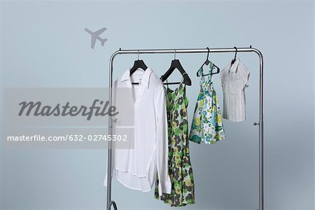 Family's summer clothing hanging on clothes rack, airplane shape in background