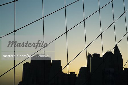 United States, New York City, silhouette of Manhattan skyline seen through Brooklyn Bridge