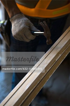 Worker holding hammer against wood