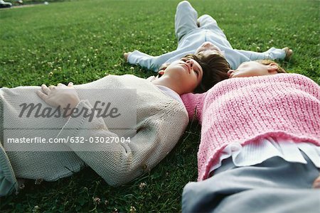 Mother and two children lying together on grass