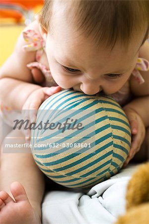 Infant chewing on striped ball