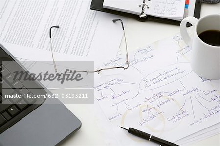 Hand written business plan on cluttered desk