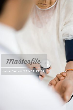 Doctor checking patient's blood pressure, over shoulder view