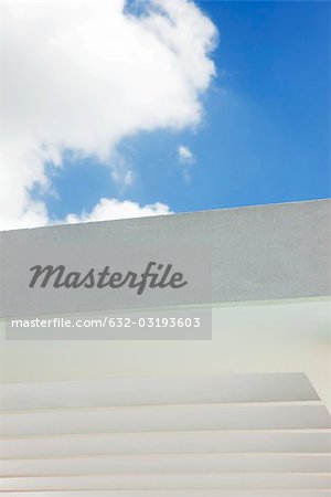 Cloud against blue sky above building wall