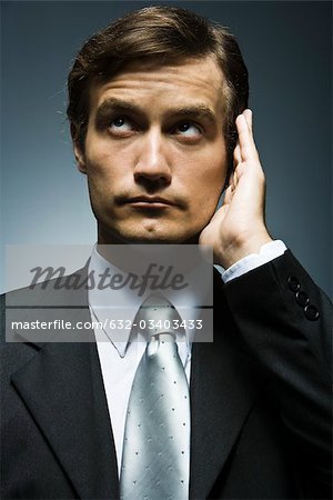 Businessman with hand cupped around ear listening attentively