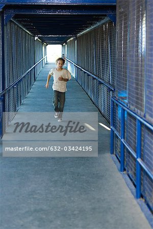 Preteen boy running down corridor, front view