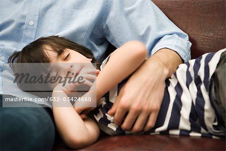 Little boy sleeping with head in father's lap