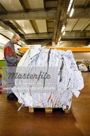 A machinist writes weight on a bale of PVC sheeting after weighing it