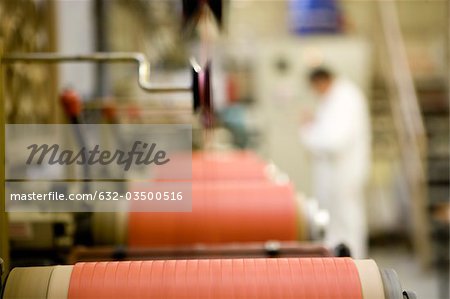 Recyclable composite textile fabrication department of factory, machinist working on thread coating machine