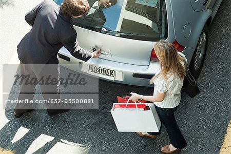 Couple opening car hatchback to stow shopping bags