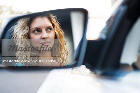 Young woman driving car, reflection in side-view mirror