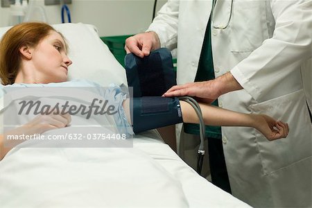 Doctor putting blood pressure cuff on patient in hospital