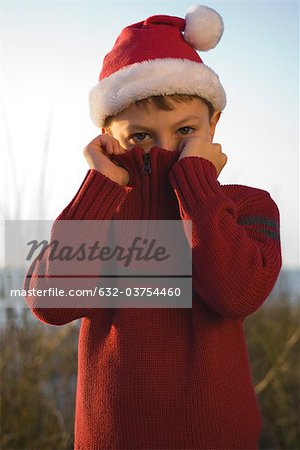 Boy covering face with sweater collar