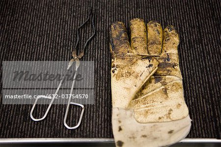 Carpet tile factory, testing lab, safety glove and crucible tongs covered in bitumen