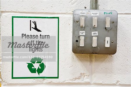 Sign reminding to turn off lights posted beside light switches