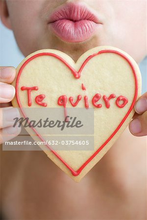 Woman puckering lips, holding up heart-shaped cookie