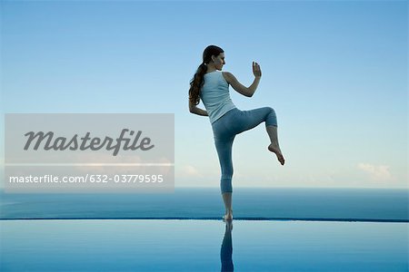 Woman practicing Tai Chi Chuan on edge of infinity pool