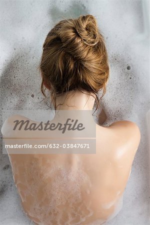 Woman relaxing in bubble bath, rear view