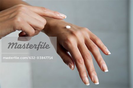 Woman moisturizing hands, cropped