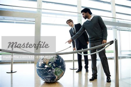 Businessmen looking at ball in lobby