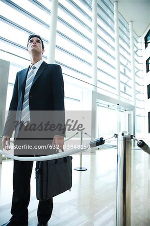 Businessman standing in lobby, looking up