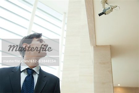 Businessman looking up at security camera