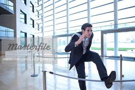 Businessman jumping over rope in lobby