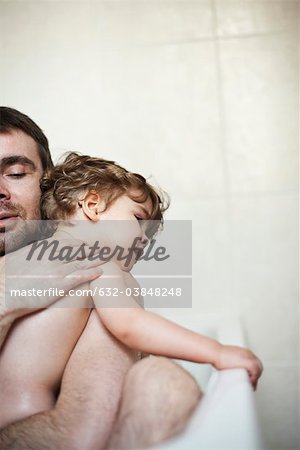 Father comforting crying son in the bath