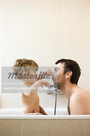 Father and toddler son playing together in the bath