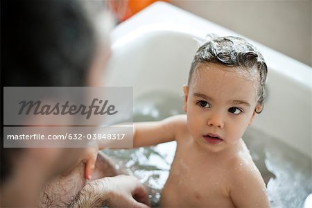 Toddler boy taking a bath with his father